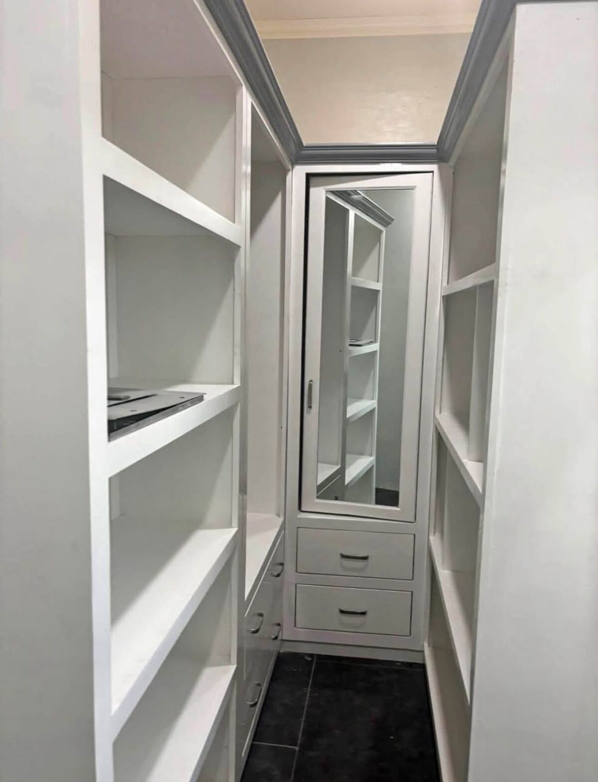 Walk-in closet with white shelving and a mirror