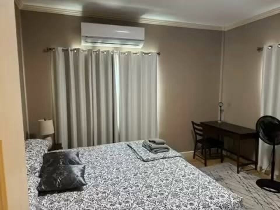Bedroom with a patterned duvet, desk and air conditioning