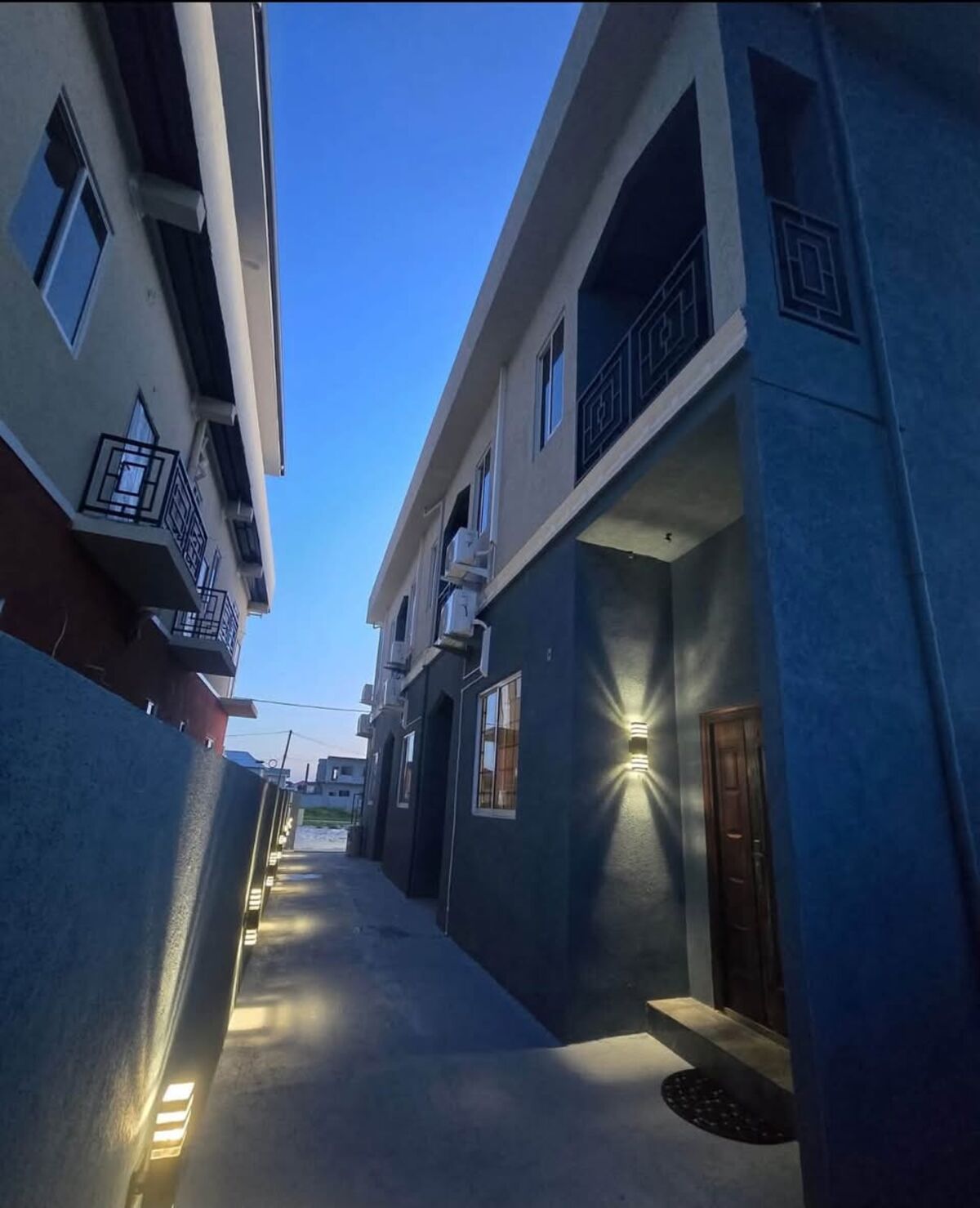 Modern two-storey building at dusk with lit walkway
