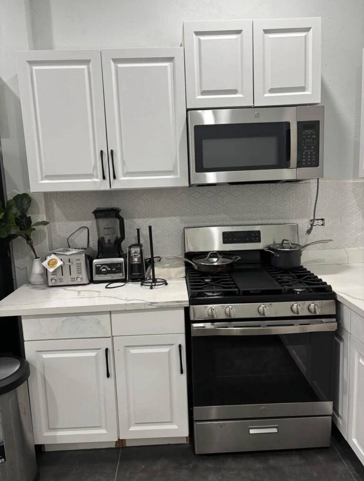 White kitchen with marble counter and stainless steel range